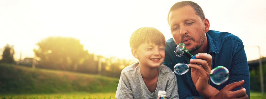 Father and son blowing bubbles together outside