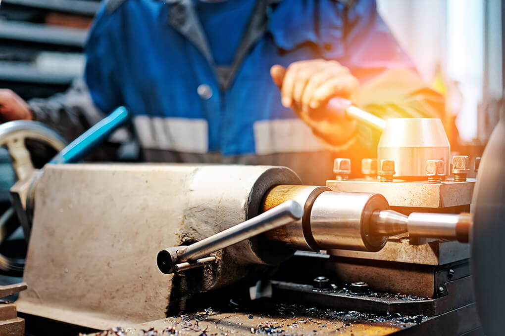 worker operating lathe in a manufacturing plant